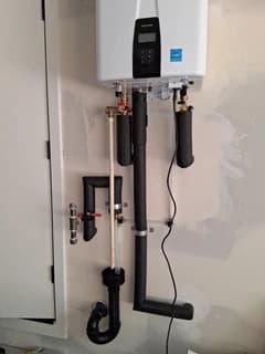 Wall-mounted water heater with completed plumbing connections