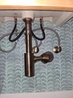 Exposed metal drain and supply connections below a bathroom sink